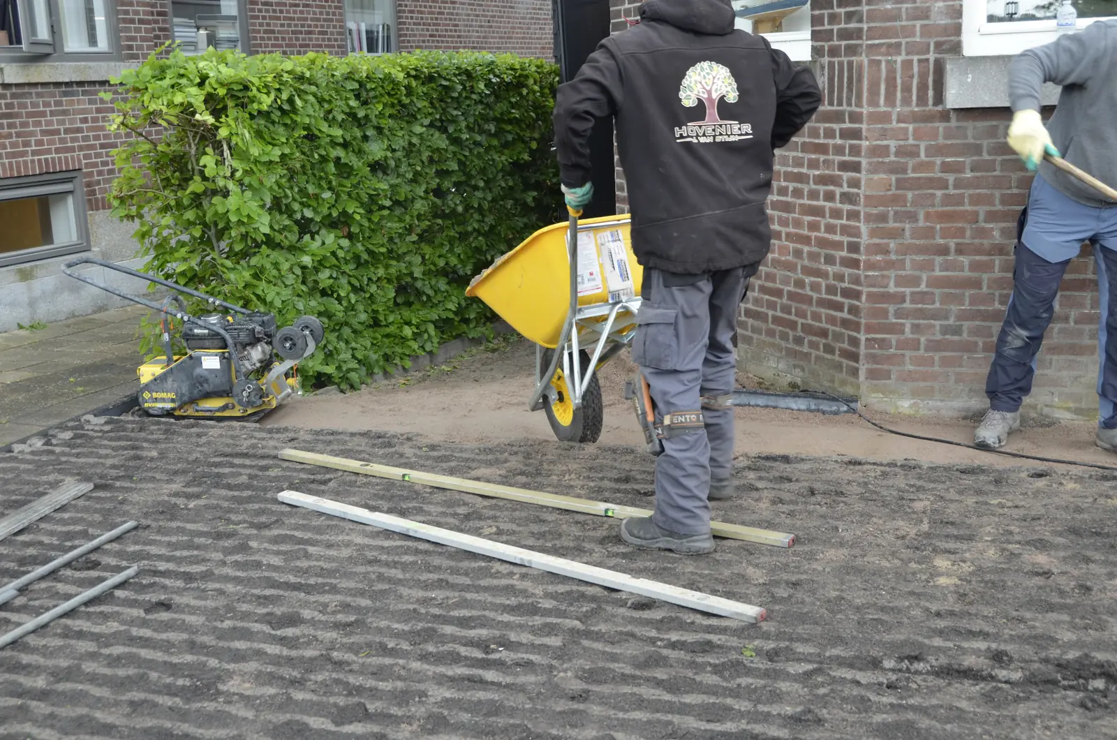 Hovenier met kruiwagen en trilplaat bij de gevel — Rotterdam-Hillegersberg