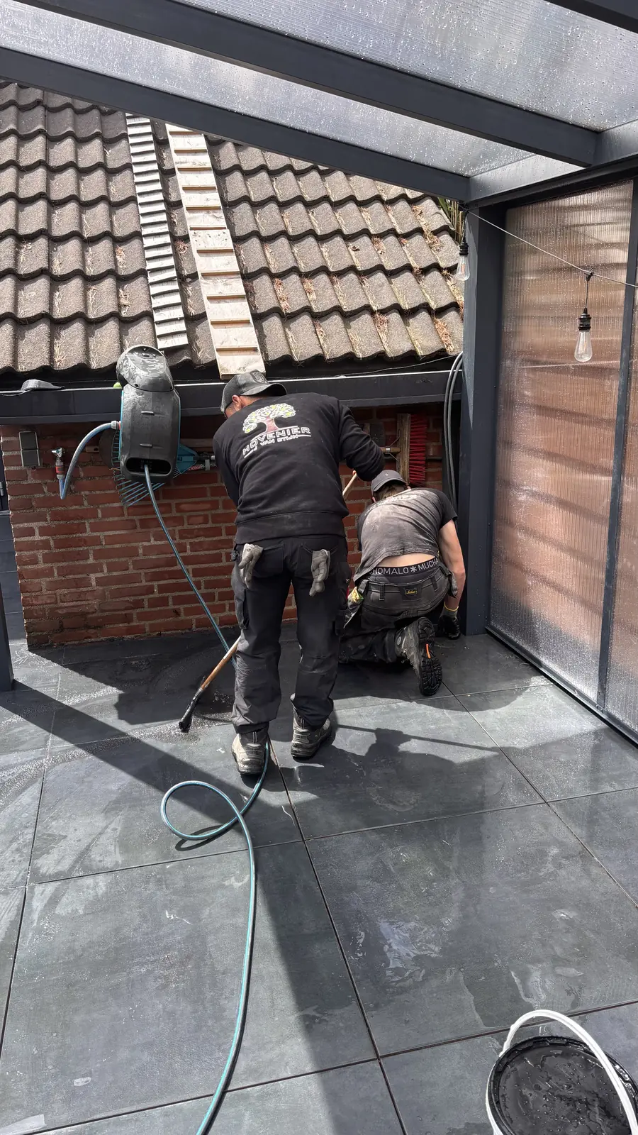 Hovenier werkt bij de gevel onder de veranda — Rotterdam